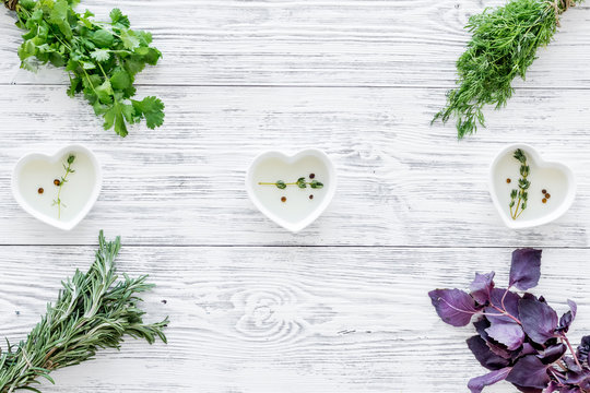 greenery with natural oil for cooking on light wooden kitchen table background top view