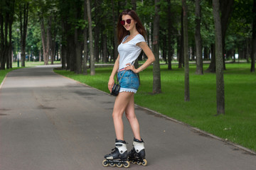 slender woman in shorts in the summer Park riding on rollers