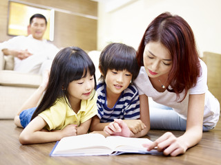 Fototapeta na wymiar asian mother reading book with two children