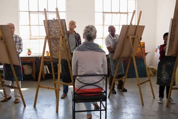 Rear view of woman sitting on chair while artist sketching