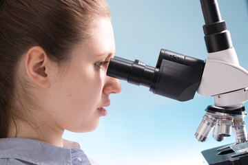 Doctor woman working  a microscope. Female scientist looking through a microscope in lab. Student girl looking in a microscope, science laboratory concept