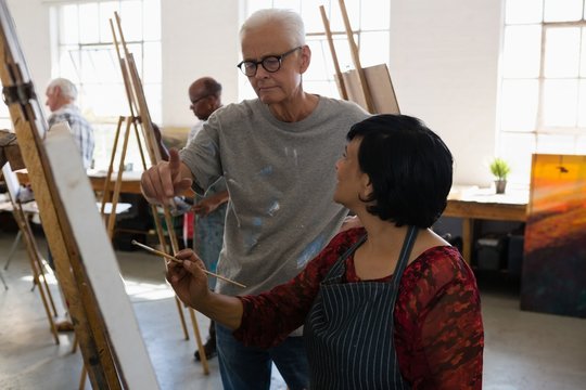 Man assisting female artist while painting