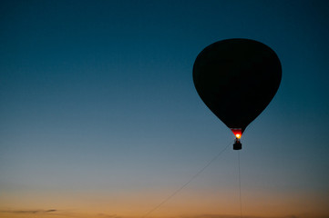 Silhouette of flying balloons with people high in sky at twilight. Freedom concept. Romantic recreation. Hot air balls competition. Autumn ballooning festival. Warm weather. Travel and tourism.