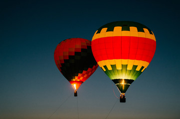 Naklejka premium Glowing and blinking balloons flight with people high in sky in night. Freedom concept. Romantic recreation. Hot air balls competition. Autumn ballooning festival. Travel and tourism. Airship journey.