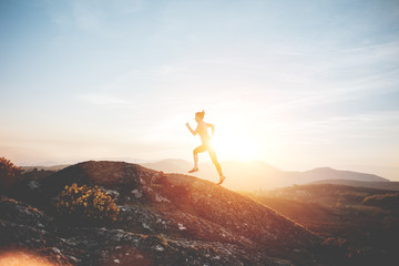 Athletic girl running in the mountains enjoying the sunset. Sport tight clothes.  Intentional motion blur.