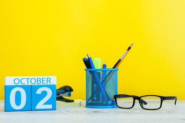 October 2nd. Day 2 of month, wooden color calendar on teacher or student table, yellow background . Autumn time. Empty space for text