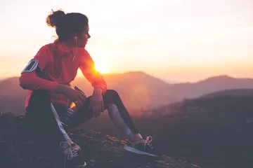 Foto op Aluminium Athletic woman resting after a hard training in the mountains at sunset. Sport tight clothes. © Alex from the Rock