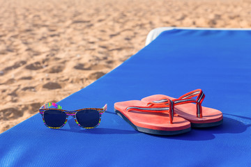 Slippers and sunglasses on sunbed at beach