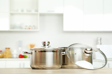 Stainless steel pots on wooden table in the kitchen