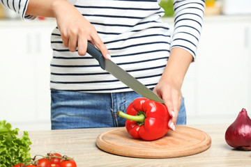 Young woman cutting red pepper in the kitchen