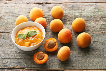 Apricot jam in bowl with mint leaf on grey wooden table