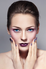 Young beautiful girl with violet sparkly make-up and manicure