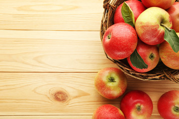 Ripe and sweet apples in basket on wooden table