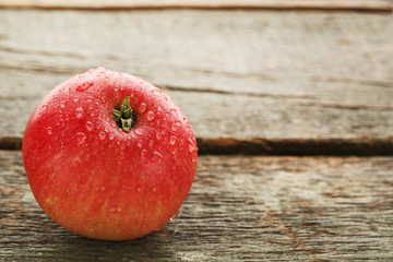 Ripe and sweet apple with water drops on wooden table