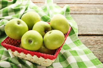 Ripe green apples in basket on wooden table