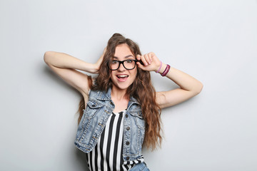 Portrait of young woman with glasses on grey background