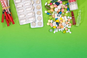 many pills, syringe isolated on green background