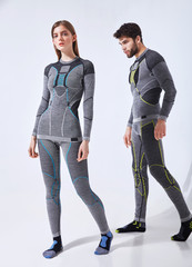 Young couple man and woman in hot sports thermal underwear for downhill skiing and extreme winter hiking - studio isolated image on white background