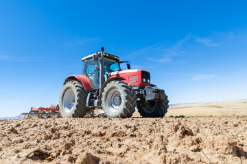 agricultural tractor in the foreground with blue sky background.