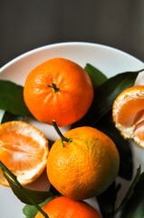 Fresh tangerines with leaves on a plate. Juicy fruit background. Top view