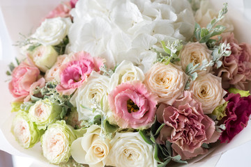 Close-up floral composition with roses and mix flowers on a light background.
