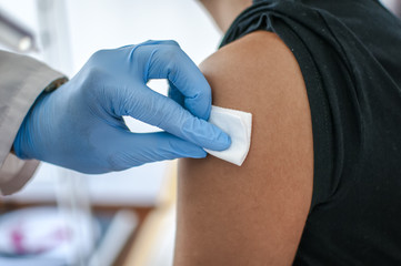 medico disinfetta la pelle di una paziente prima di fare una vaccinazione