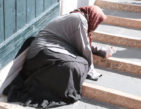 gypsy woman with headscarf and long skirt begging people on the