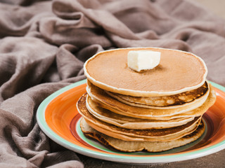 Close up view of homemade pancakes. Stack of pancakes with butter on brown concrete background.