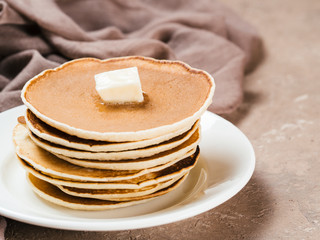 Close up view of homemade pancakes. Stack of pancakes with butter on brown concrete background.