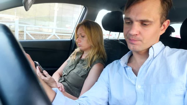 man driver solicits girl of a passenger, who looks into a smartphone. 4k, slow-motion