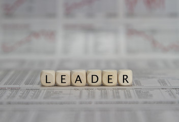 Leader word built with letter cubes on newspaper background