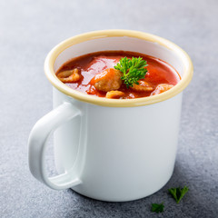 Delicious homemade tomato soup with meatballs in enamel mug. Healthy food concept.
