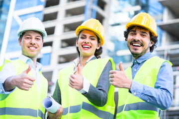 Team of civil engineers and architects at construction site giving thumbs up gesture and saying OK