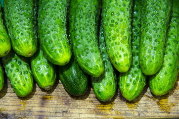 
Wet cucumbers are tiered on a board.