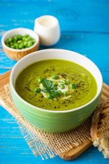Green pea soup in bowl on wooden table