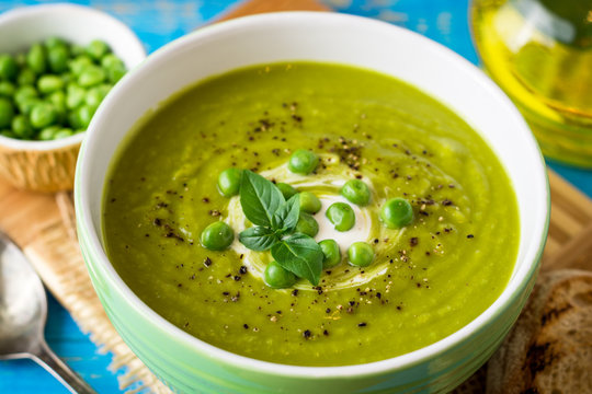 Green pea soup in bowl on wooden table