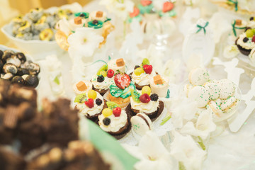 Delicious and tasty dessert table with cupcakes shots at reception closeup