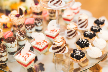 Delicious and tasty dessert table with cupcakes shots at reception closeup