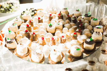 Delicious and tasty dessert table with cupcakes shots at reception closeup