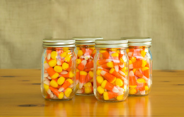  4 mason jars filled with candy corn on a wooden table