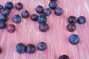 Ripe plums on a pink wooden background