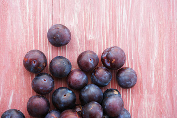 Ripe plums on a pink wooden background