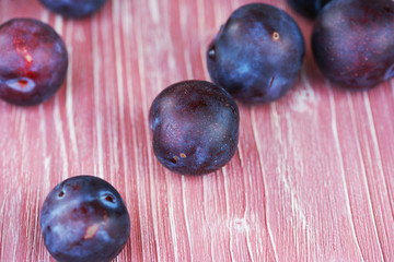 Ripe plums on a pink wooden background