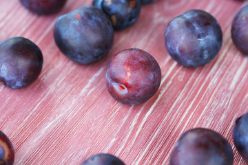 Ripe plums on a pink wooden background