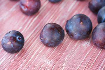 Ripe plums on a pink wooden background