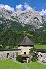 Fototapeta na wymiar Burgmauer und Turm von Burg Hohenwerfen mit Tor, Burghof und den Gipfeln des Tennengebirges im Hintergrund