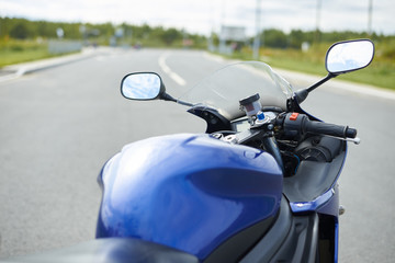 Details of body of modern powerful motorcycle on empty road with copy space for your text or advertising conctent. Outdoor summer shot of custom-built blue motorbike. Transport and extreme lifestyle