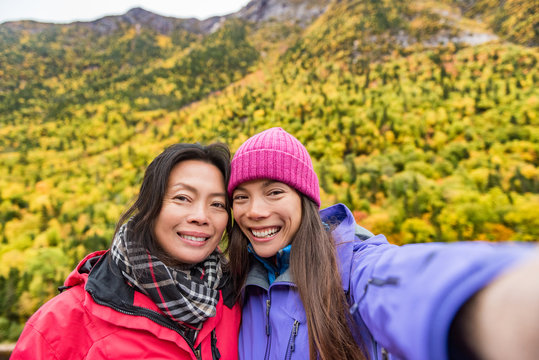 Mother daughter family self portrait selfie women taking picture with smartphone mobile app on outdoor forest hike in autumn nature landscape. Hikers lifestyle.