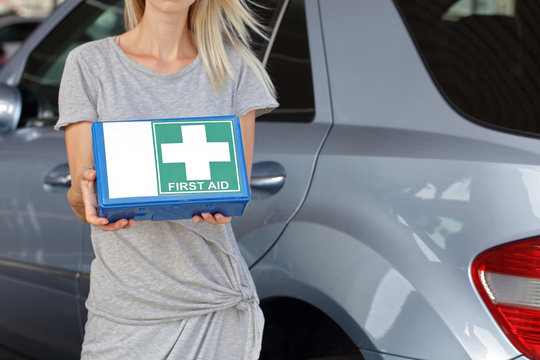 Responsibility And Safety On Road Concept. Woman Holding First Aid Kit For Car.