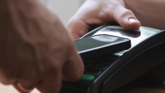 Close-up shot of person using NFC technology on smart phone to pay